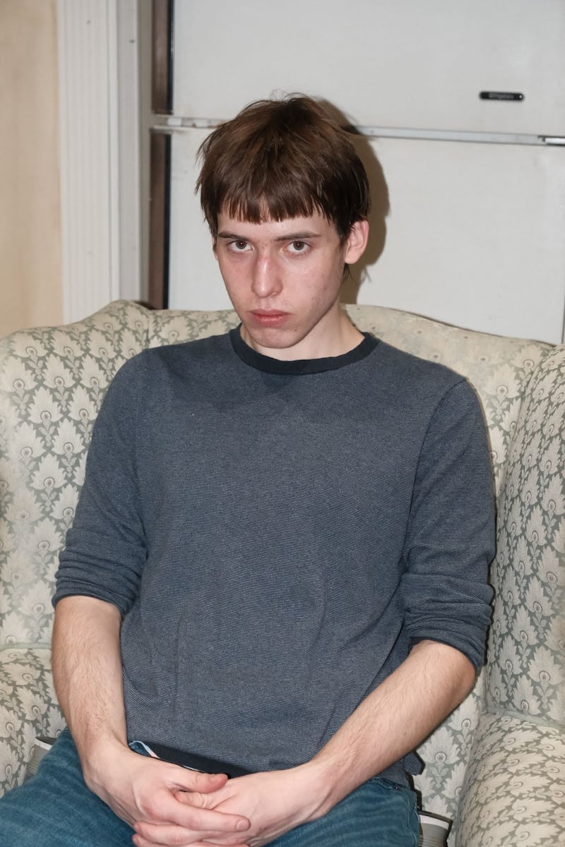 Photo of a young man sitting with his hands folded in a chair