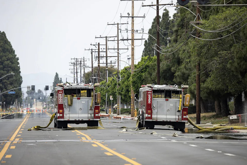 Two red fire trucks parked in the middle of a street. (Kayla Bartkowski / Los Angeles Times via Getty Images)
