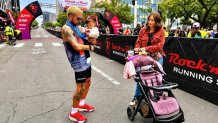 Anthony Solis hold his young daughter, Amelia, after winning the half marathon. Sunday. His wife, Alysia, cheered him on from the sidelines, May 31, 2026.