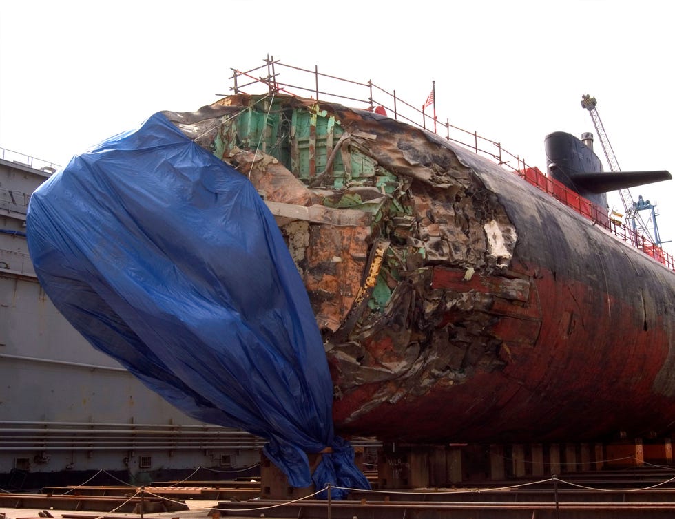 Damaged submarine undergoing repairs at a dock.