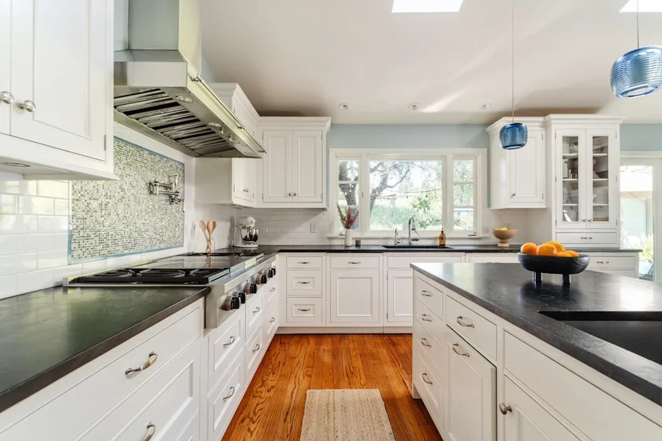 A detailed view of the kitchen's cooking area, showcasing a large stainless steel range under a professional vent hood.