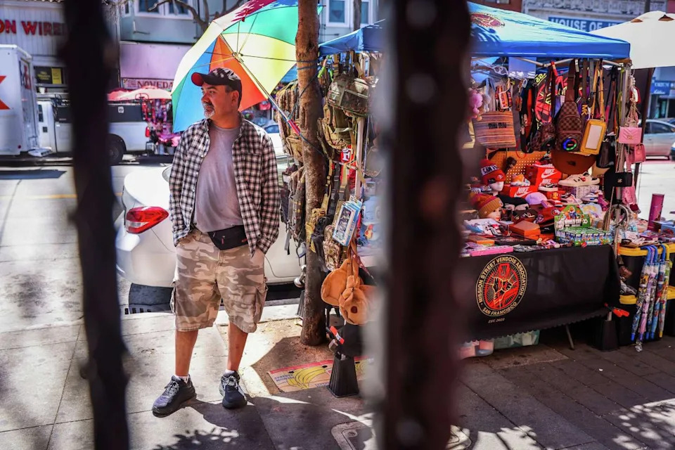Rodrigo Lopez stands next to his legal vending stand on Mission Street near 24th Street in San Francisco. (Gabrielle Lurie/S.F. Chronicle)