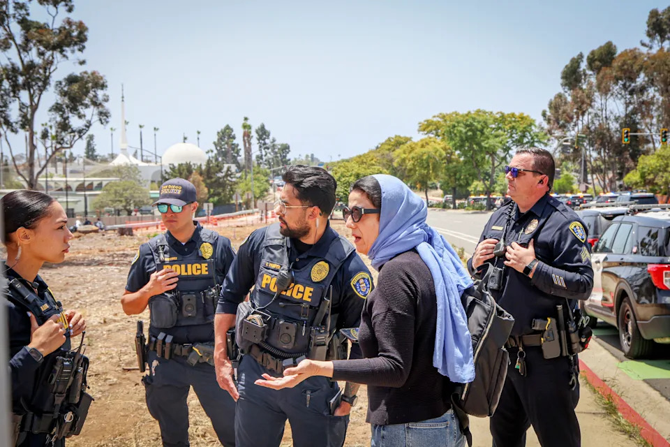 Police speak with a woman near the Islamic Center in San Diego after multiple people were killed, including an armed security guard.