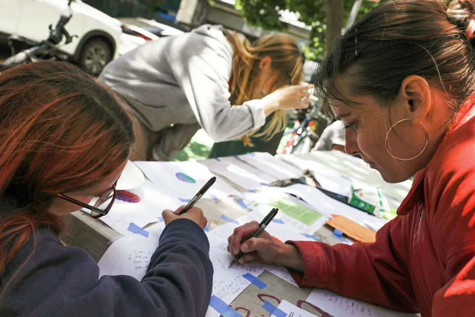 Clara Bacmerster, right, of San Francisco, and others write notes not survivors on a large poster board during a vigil to honor survivors of an alleged mass strip search at the San Francisco County Jail on May 22, 2026, in San Francisco. (Lea Suzuki/S.F. Chronicle)