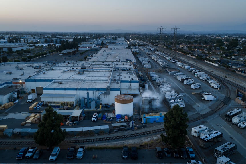 A drone shot of a tank pluming smoke in an industrial area