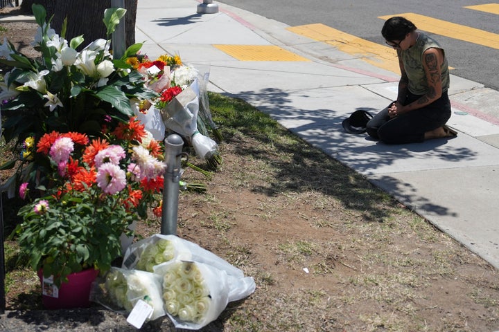 A woman prays beside flowers placed outside of the Islamic Center of San Diego the day after the shooting. 