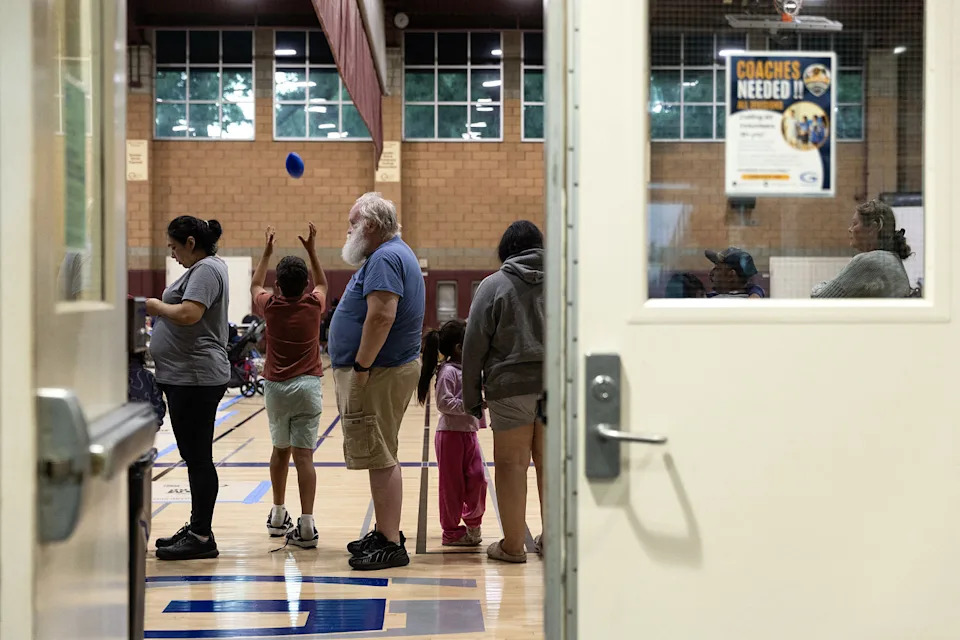 People stand in a line in a gymnasium. (Blake Fagan / AFP via Getty Images)
