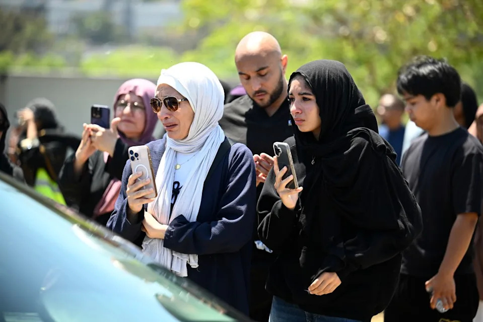 Mourners look on as hearses leave with the caskets of the three victims. Denis Poroy for CA Post