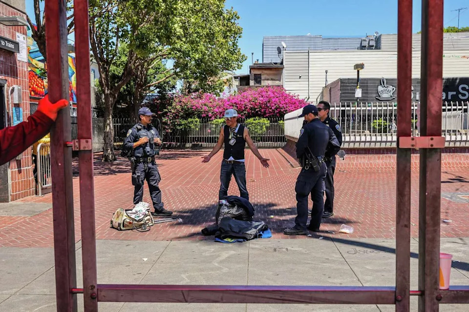 Mission Station police captain Sean Perdomo, right, argues with a man, center, on Mission Street near 24th Street who was selling various items on the street in San Francisco, Calif., on Thursday, May 21, 2026. The police make their presence known in an attempt to curb illegal vending. (Gabrielle Lurie/S.F. Chronicle)