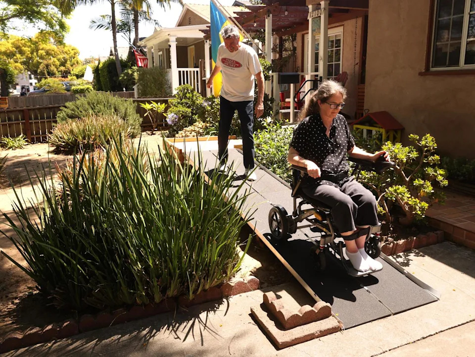 Barbara Durieux Coanda and her husband, John Coanda, make their way down the ramp in front of their home in Mar Vista.
