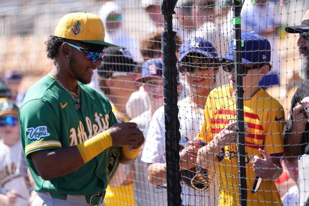 The Athletics' Leo de Vries talks with fans as he signs autographs prior to a spring training baseball game against the Dodgers, Saturday, March 21, 2026, in Phoenix. (AP Photo/Ross D. Franklin)