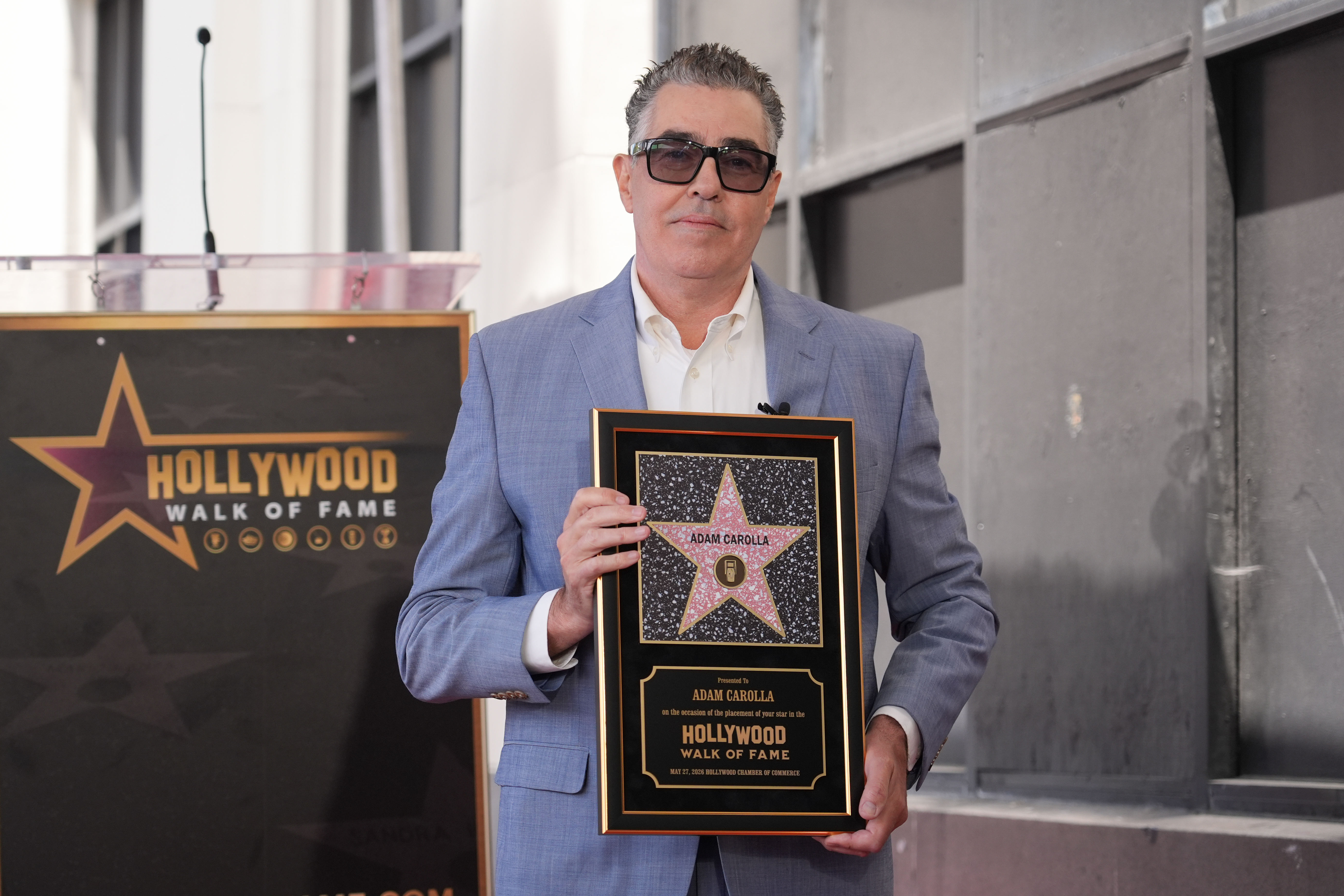 Adam Carolla poses with his new star during a ceremony...