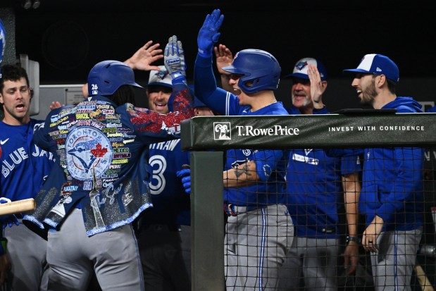 Charles McAdoo #26 of the Toronto Blue Jays, wearing the jacket, celebrates in the dugout with teammates after hitting a two-run home run in only his third Major League at-bat in the seventh inning against the Baltimore Orioles at Oriole Park at Camden Yards on May 29, 2026 in Baltimore, Maryland.  (Photo by Jamie Sabau/Getty Images)
