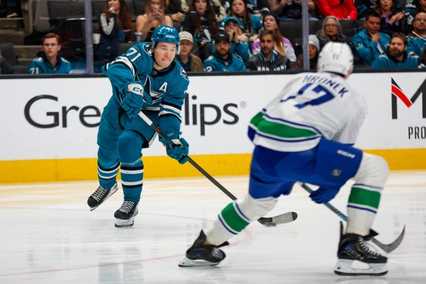 San Jose Sharks' Macklin Celebrini (71) hits the puck against Vancouver Canucks' Filip Hronek (17) in the first period at SAP Center in San Jose, Calif., on Saturday, April 11, 2026. (Shae Hammond/Bay Area News Group)