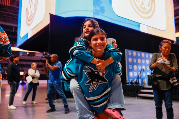 Luna ElNaggar, 9, of San Jose, rides on her sister Toci ElNaggar's, 11, back before a press conference where Professional Women's Hockey League officially announces a team in San Jose at SAP Center in San Jose, Calif., on Tuesday, May 19, 2026. Both sisters play hockey for the Jr. Sharks. (Shae Hammond/Bay Area News Group)