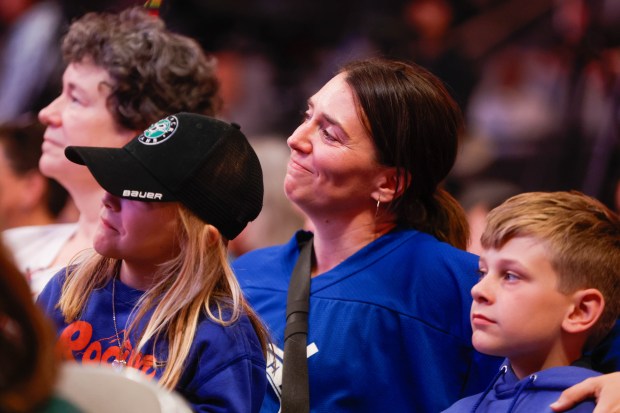 Steph Hardinger, of San Jose, holds her children Linnea Harbinger, 6, and Silas Harbinger, 8, while listening to Brandi Chastain speak during a press conference where Professional Women's Hockey League officially announces a team in San Jose at SAP Center in San Jose, Calif., on Tuesday, May 19, 2026. Steph plays in the Northern California Women's Hockey League. (Shae Hammond/Bay Area News Group)