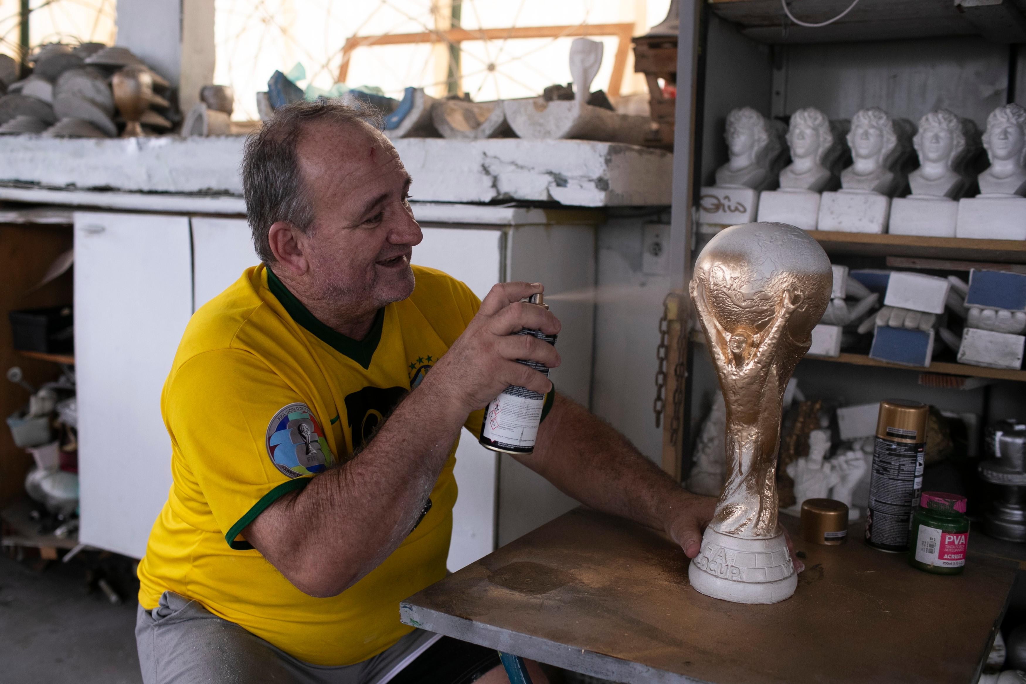 Jarbas Meneghini Carlini sprays a FIFA World Cup trophy replica he made.
