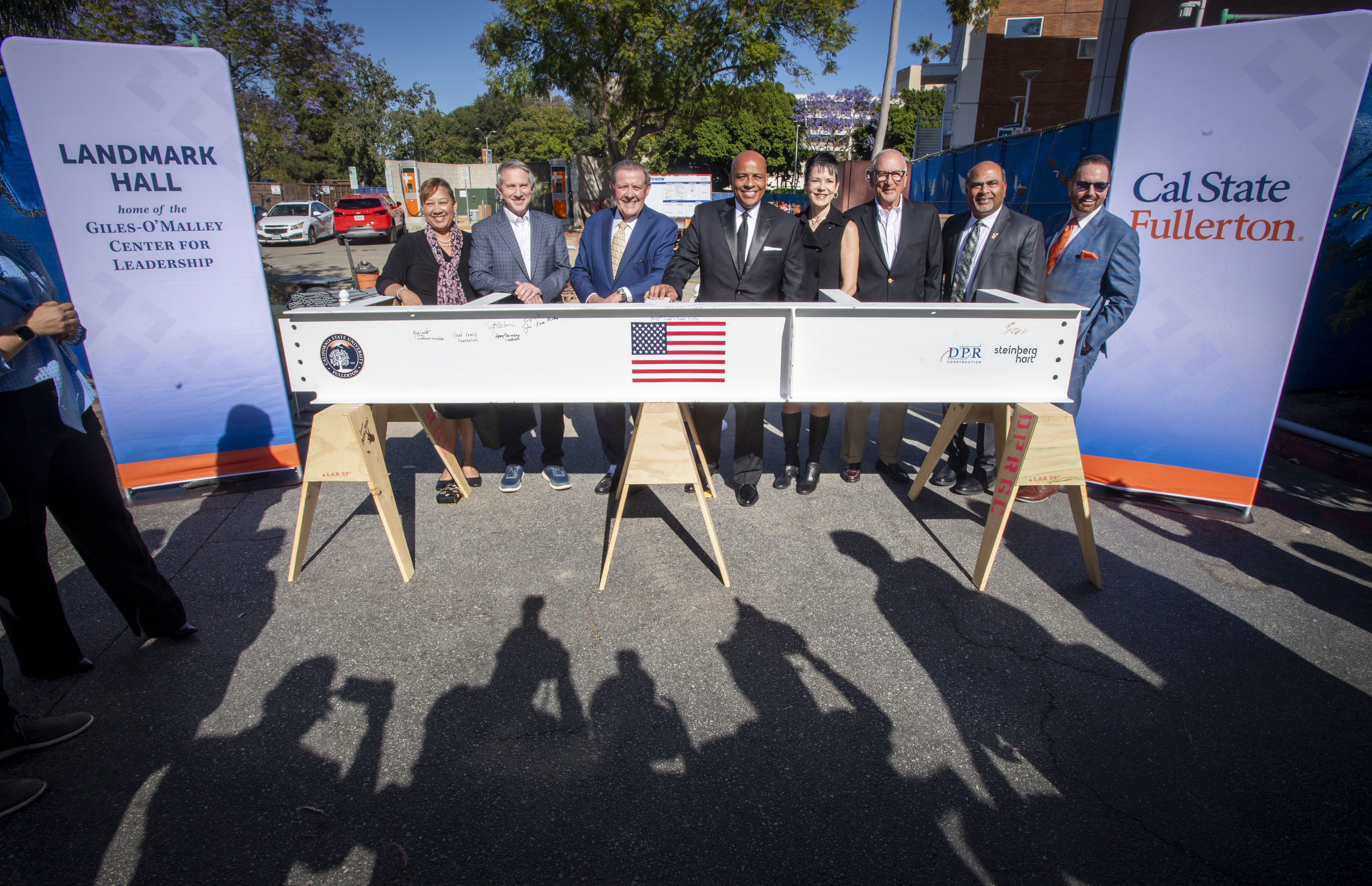 Dignitaries have their photo made near a beam that is...