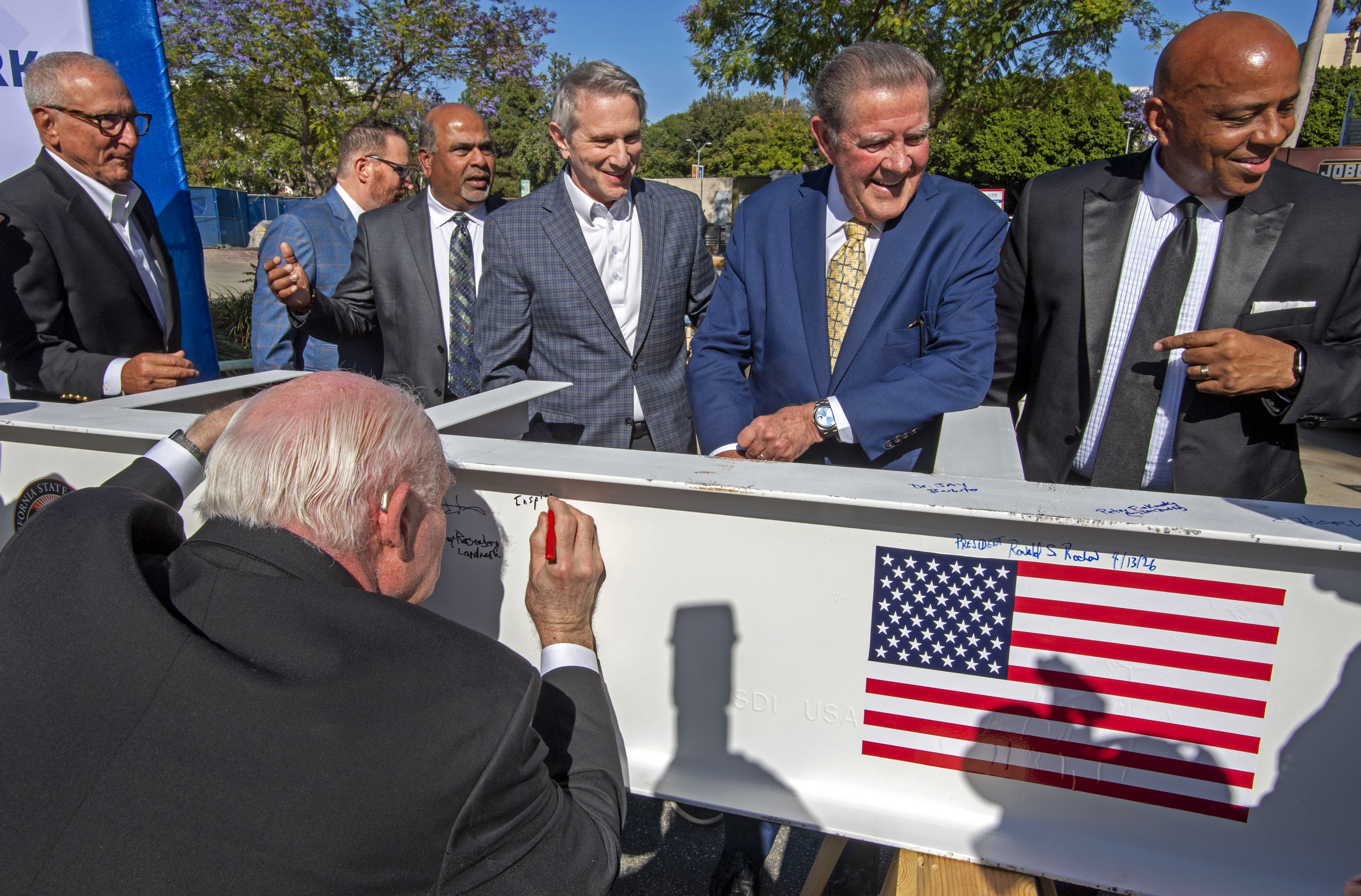 Dignitaries gather to have their photo made near a beam...