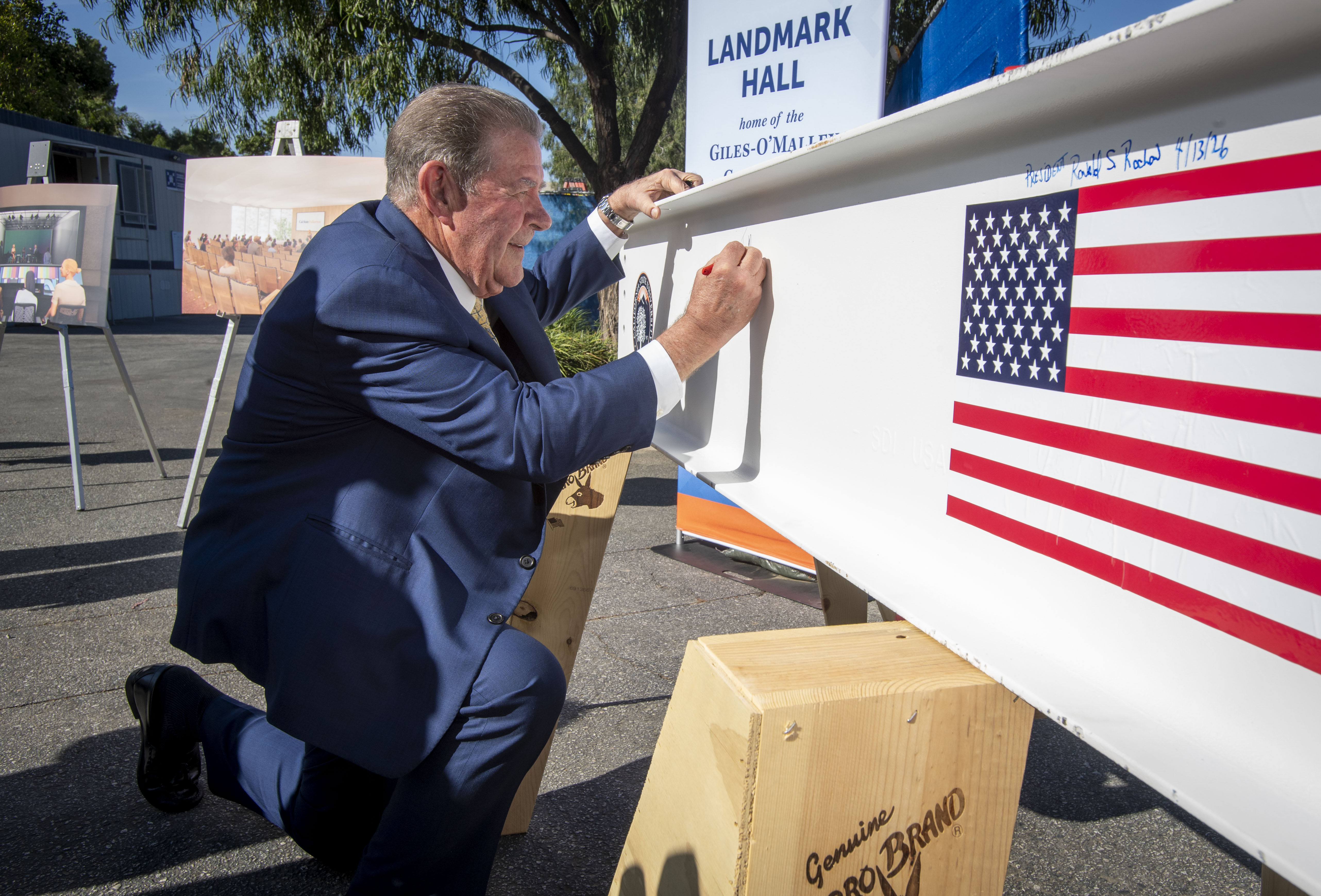Terry M. Giles signs his name on a beam to...