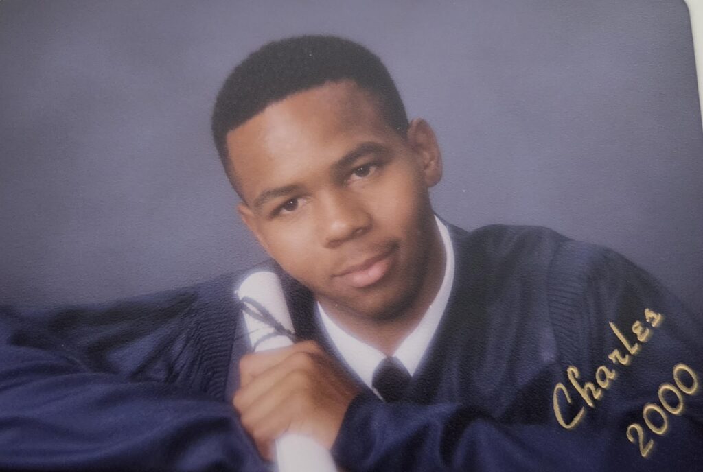 Charles Long's high school graduation photo, holding a scroll of paper
