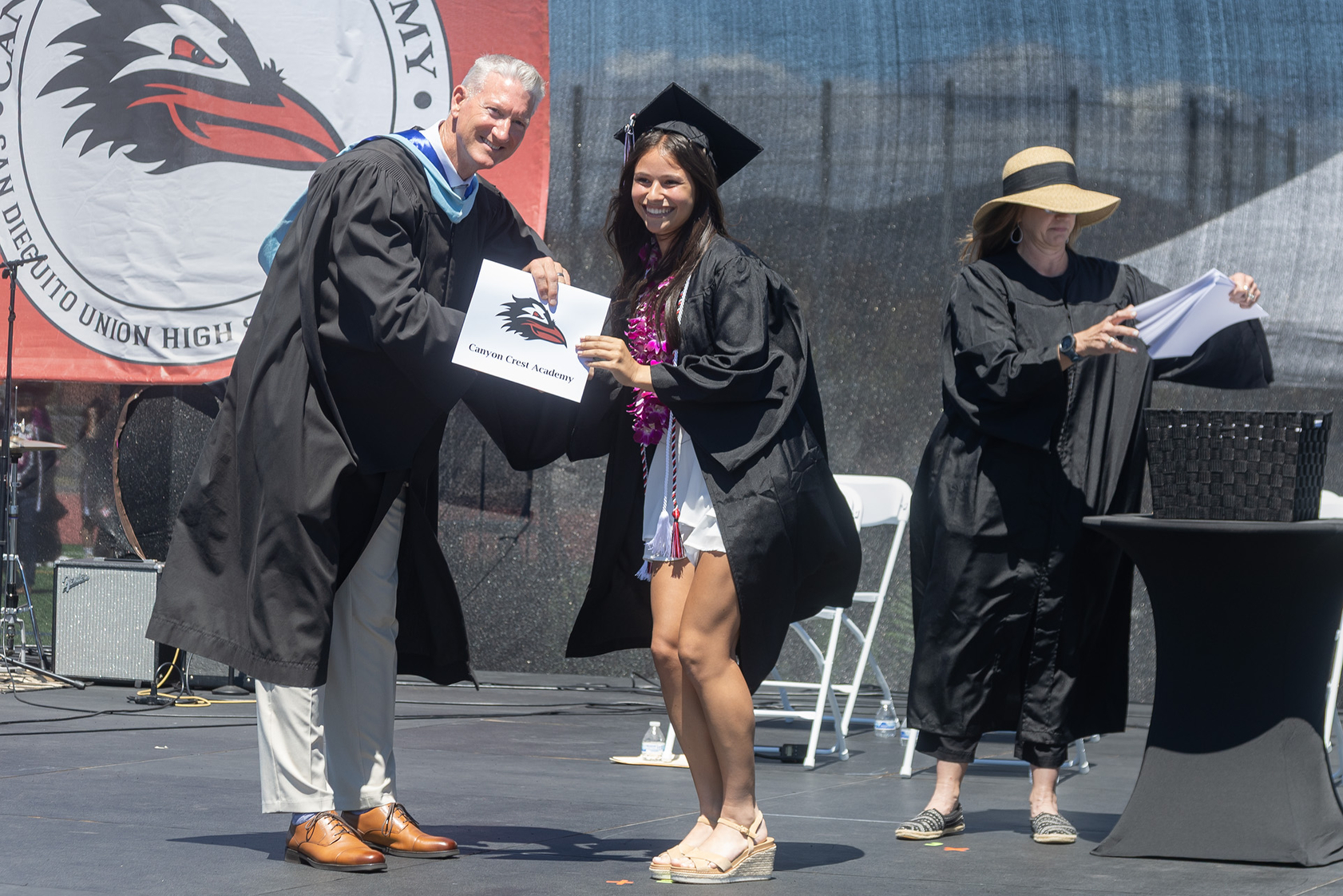 Principal Brett Killeen presents a diploma to a CCA graduate...