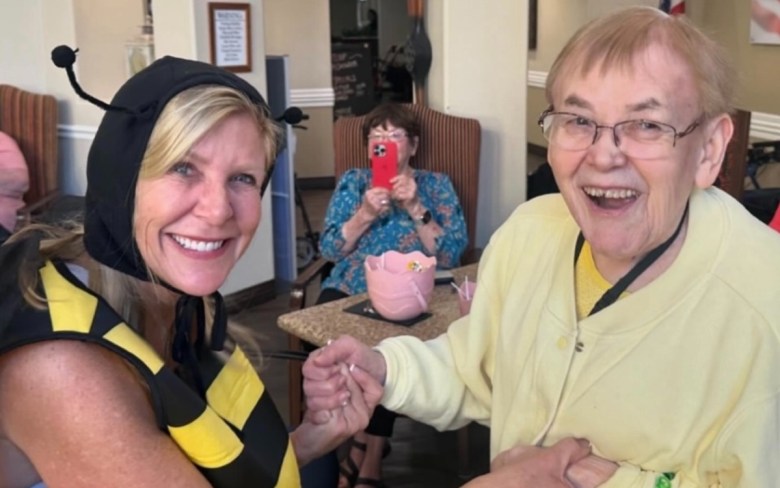 Woman in a bee costume dancing with an older adult at a senior living happy hour