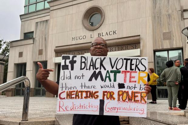 Travis Jackson stands outside the federal courthouse with a sign.