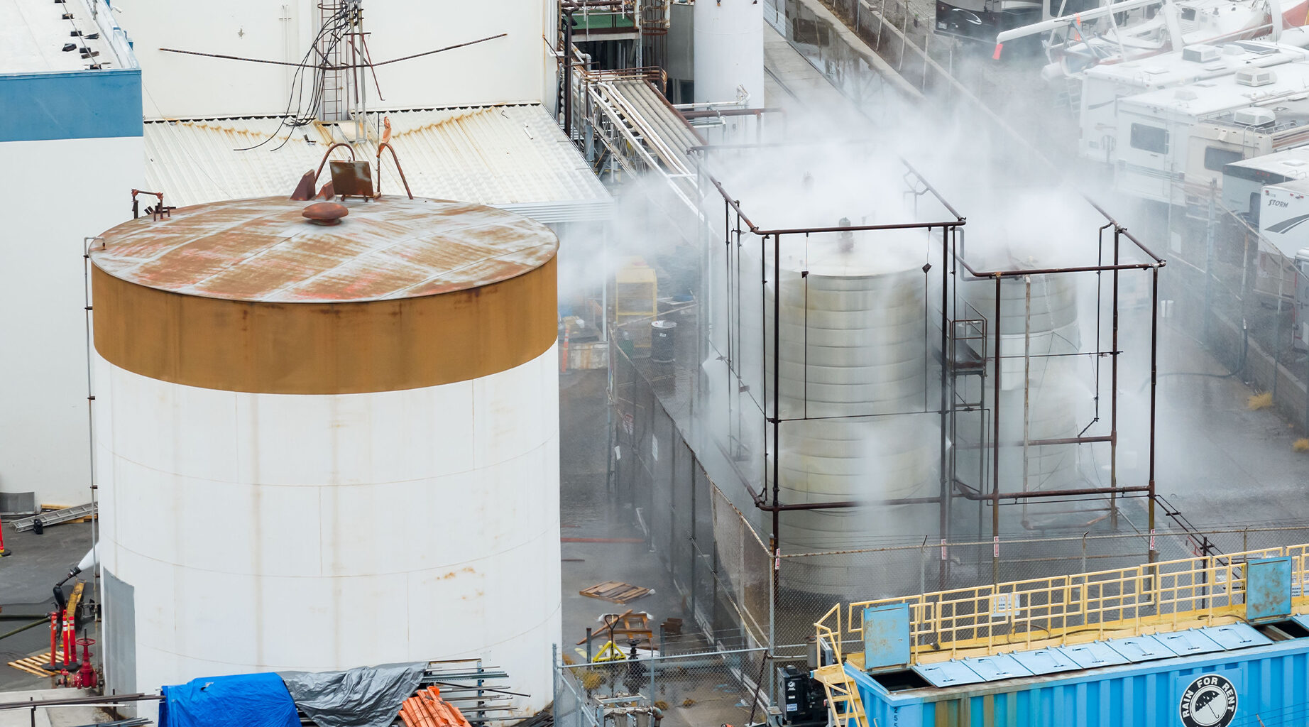 Water is sprayed on a damaged tank at GKN Aerospace in Garden Grove, Calif., on Sunday, May 24, 2026, after the tank containing a chemical used to make plastic parts overheated Thursday. (AP Photo/Ethan Swope)