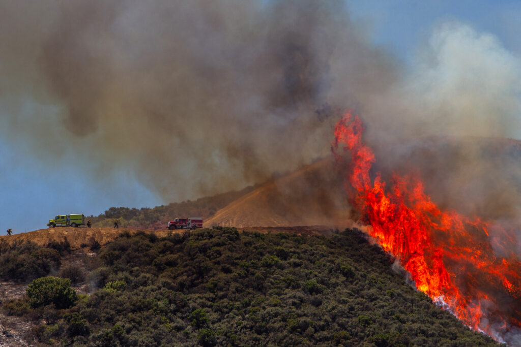 Firefighters work to combat a hotspot in the hills while the Sandy Fire continues to burn near a residential area on Wednesday in Simi Valley, Calif. Credit: Apu Gomes/AFP via Getty Images