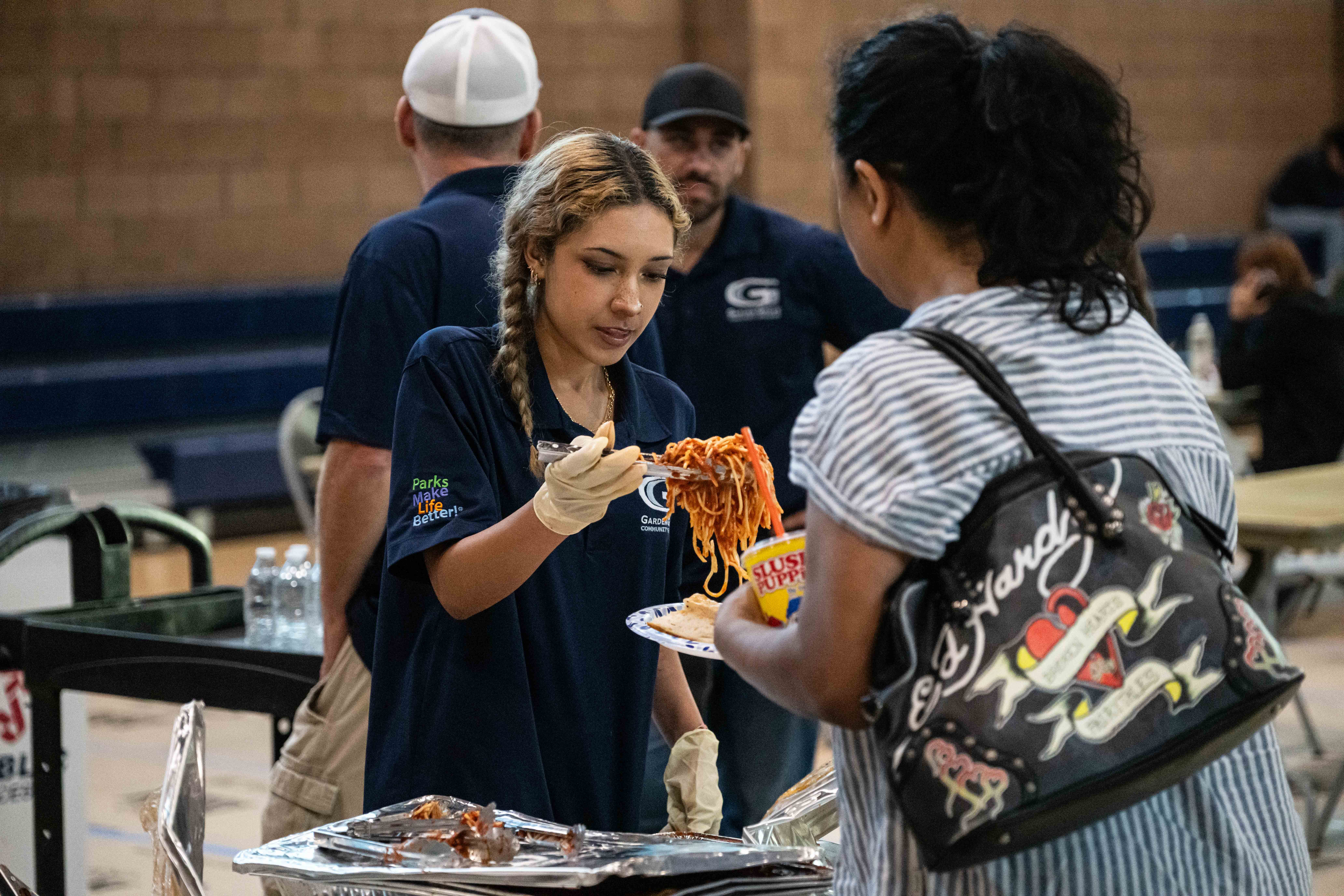 Garden Grove Sports & Recreation Center employees feed the evacuees a Spaghetti dinner as families await the results of the Chemical Leak in Garden Grove, California in Garden Grove, California, United States on May 22, 2026. (Photo by Jon Putman/Anadolu via Getty Images)