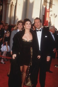 29th March 1989: Married American actors Demi Moore and Bruce Willis hold hands as they walk the red carpet, arriving at the Academy Awards, Shrine Auditorium, Los Angeles, California. Moore wears a black minidress, and a jacket robe. (Photo by Darlene Hammond/Hulton Archive/Getty Images)