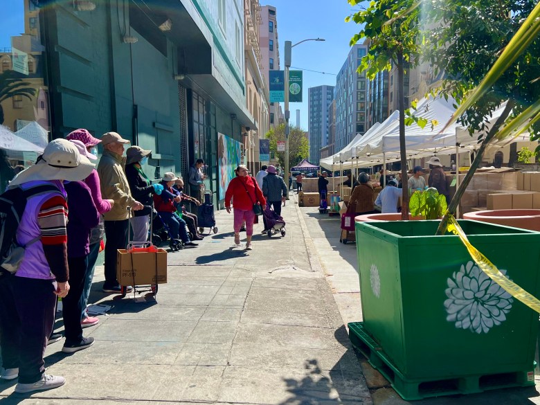 Seniors wait in line for groceries on city sidewalk