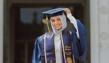 Portrait of Hannah Rabbani in her UC Berkeley graduation regalia. She is wearing a navy gown, a custom stole with her name, and a white hijab.
