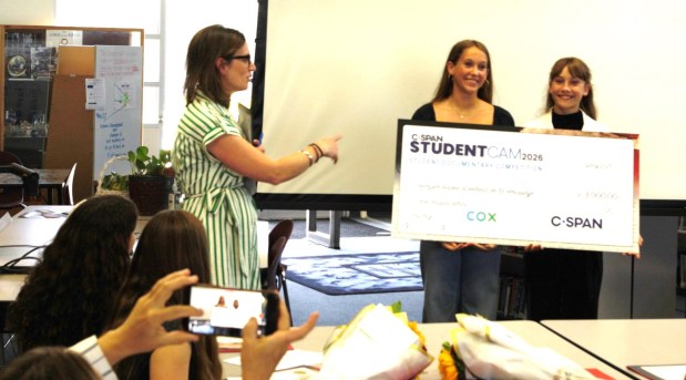 Rachel Katz, affiliate relations manager at C-SPAN, presents Correia Middle School eighth-graders Harper Haden and Helena de la Houssaye with a ceremonial check for $3,000 for winning first prize for their documentary "This is What Democracy Looks Like." (Tyler Faurot)