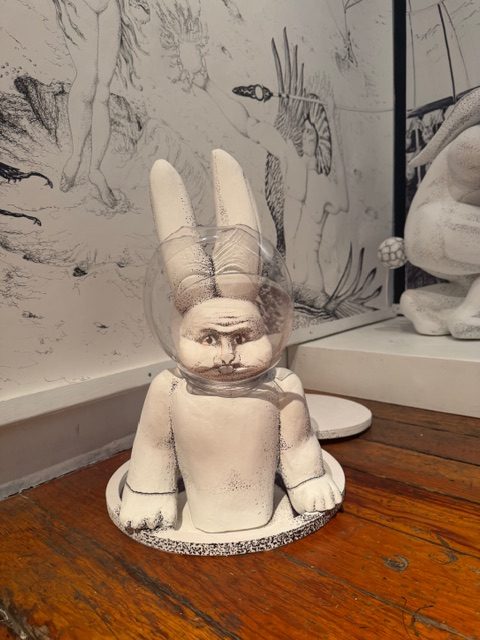 Galactic Nature sculpture of figure with helmet and detailed space-themed wall drawing behind
