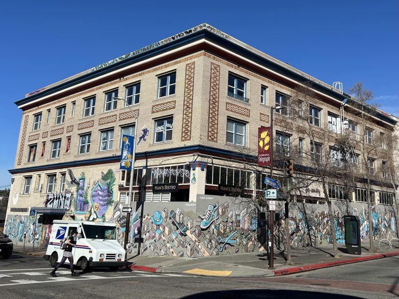 A three-story apartment building with a brick facade; the ground floor is boarded up and covered with a mural