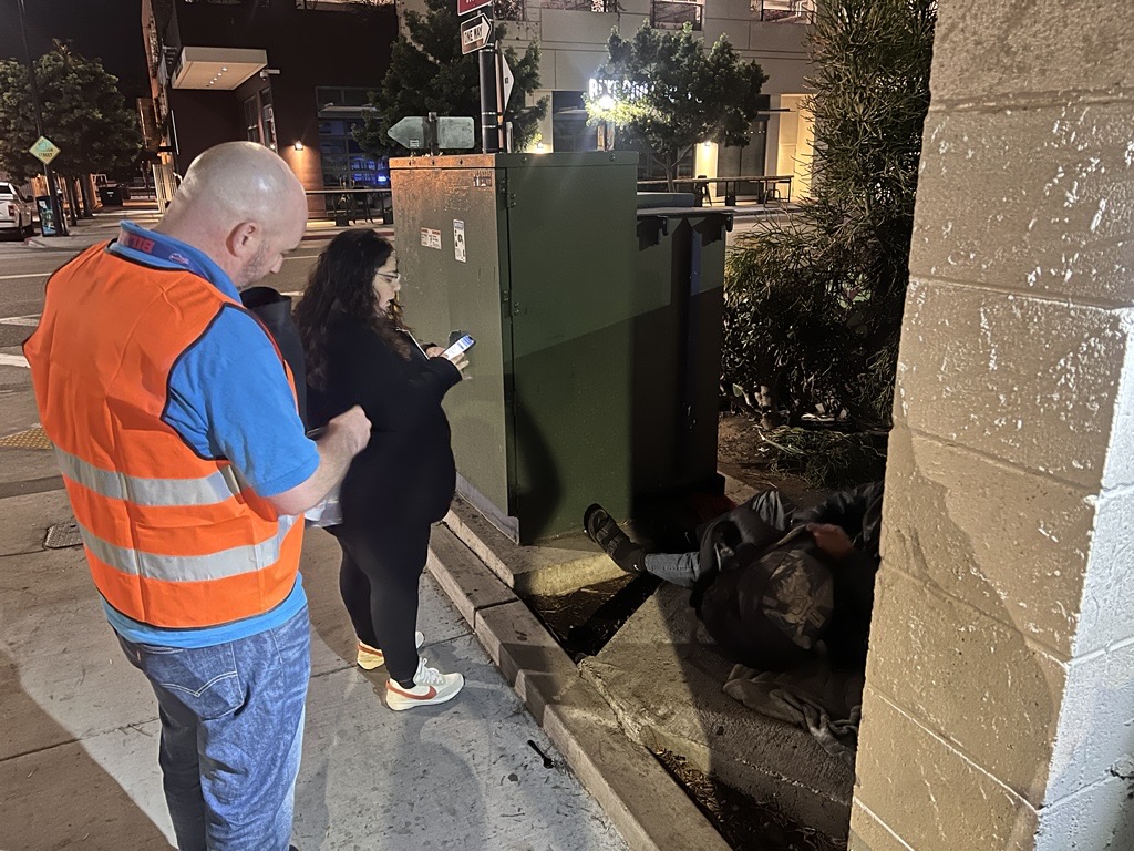 Two County employees speak with a person experiencing homelessness in the early morning hours.