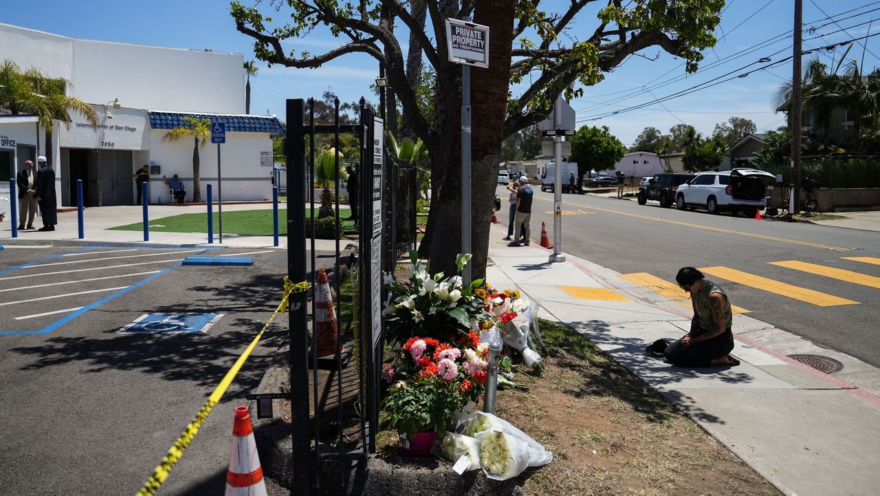 Nicole Witherow prays beside flowers placed outside of the Islamic Center of San Diego, a day after a shooting, Tuesday, May 19, 2026, in San Diego. (AP Photo/Jae C. Hong)