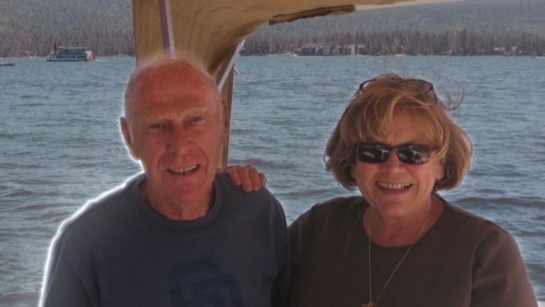Husband and wife pose on a boat on a lake