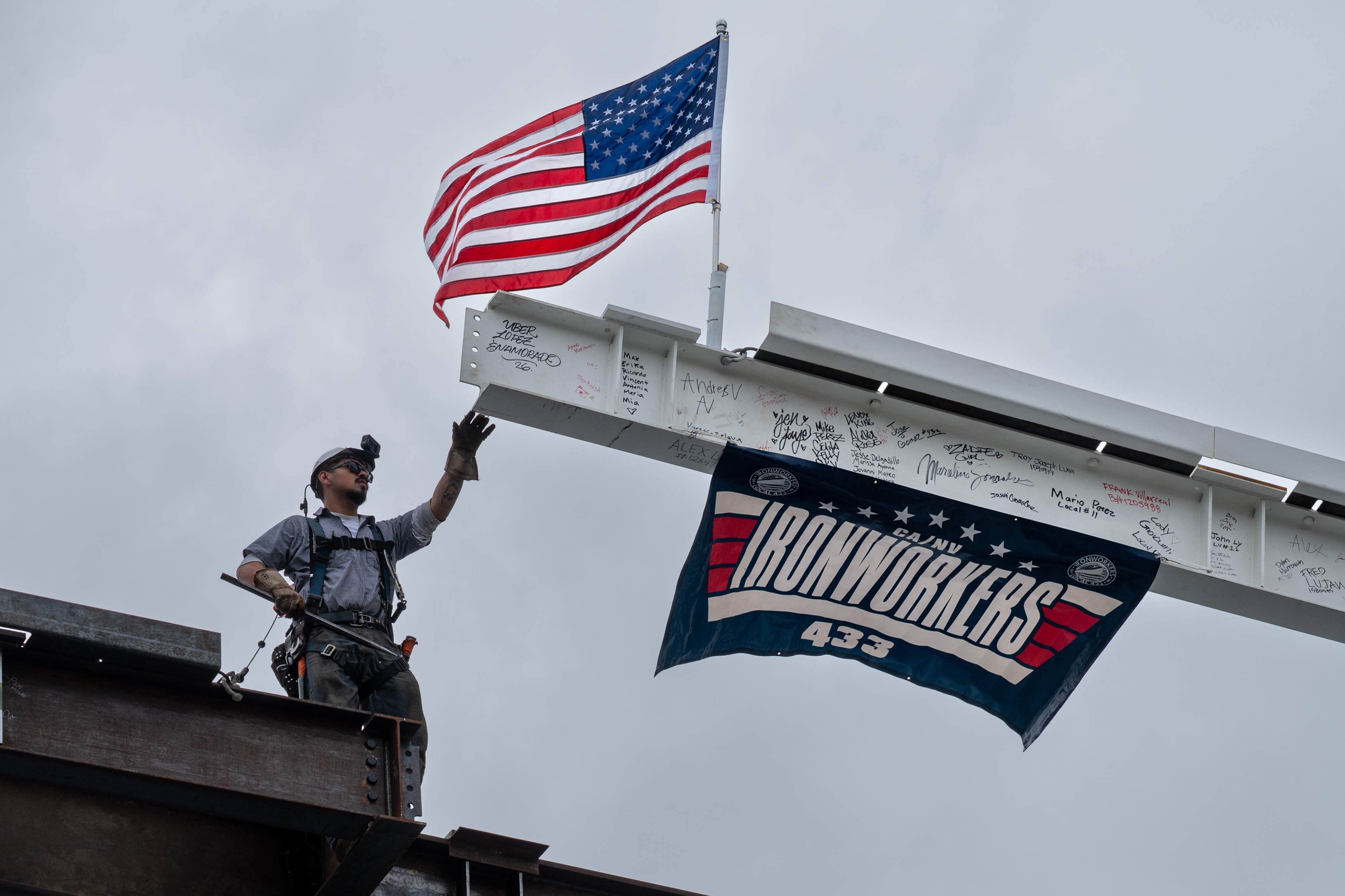 Workers place the last steel beam on top of the...