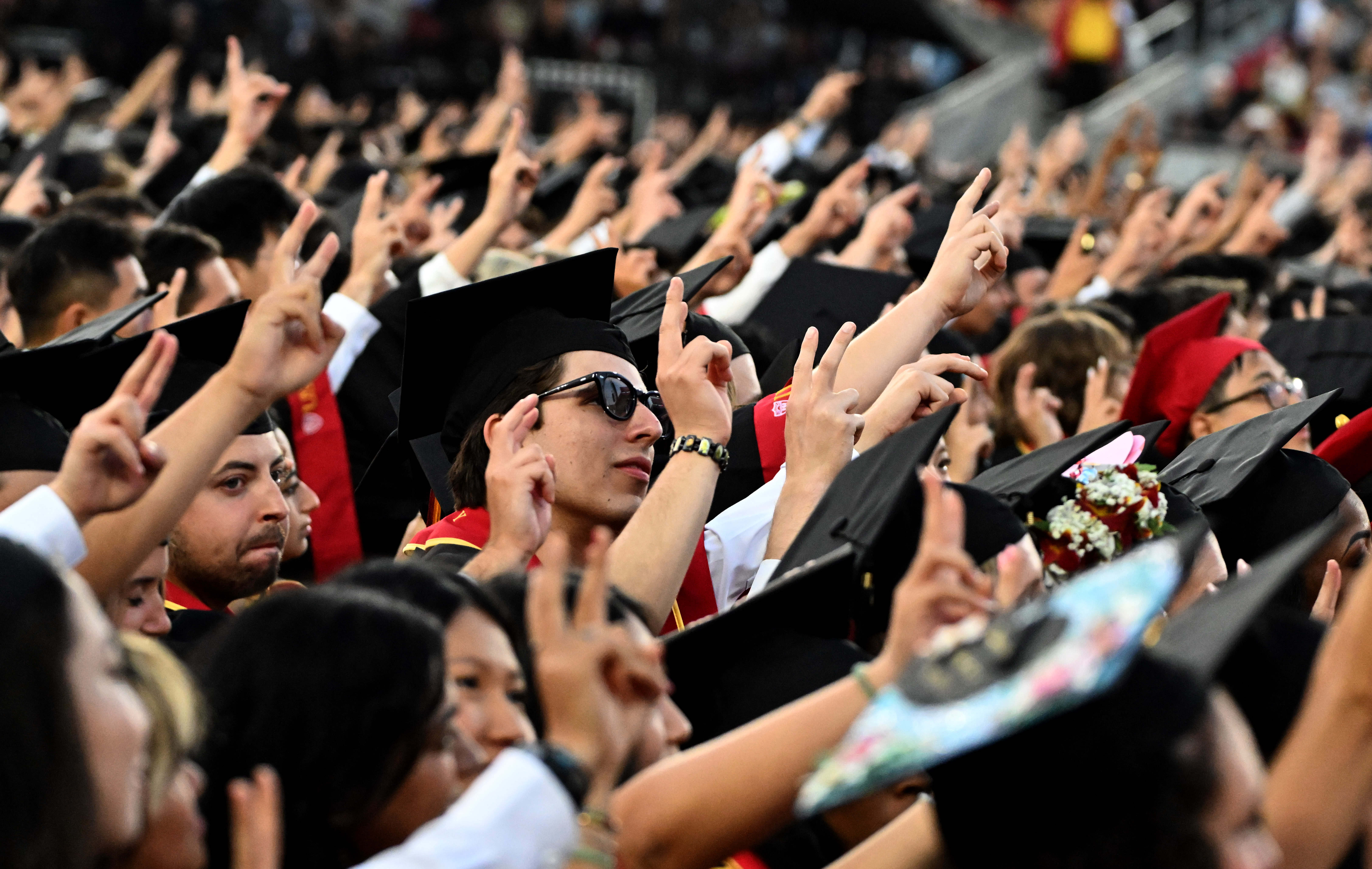 Graduates give the victory sign during USC’s 143rd commencement ceremony...