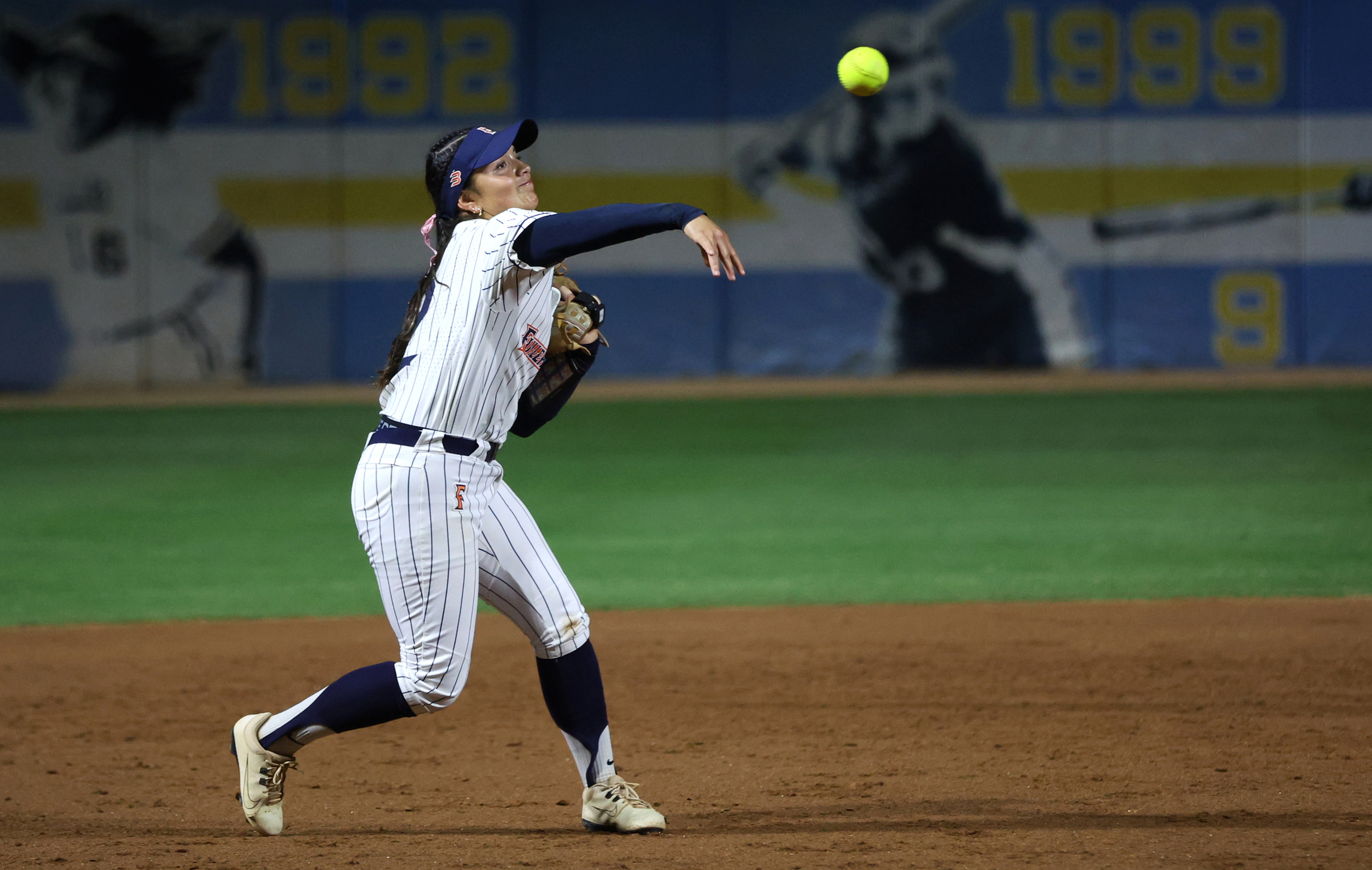 Cal State Fullertonâs Sarah Coccillos tosses the ball to first...