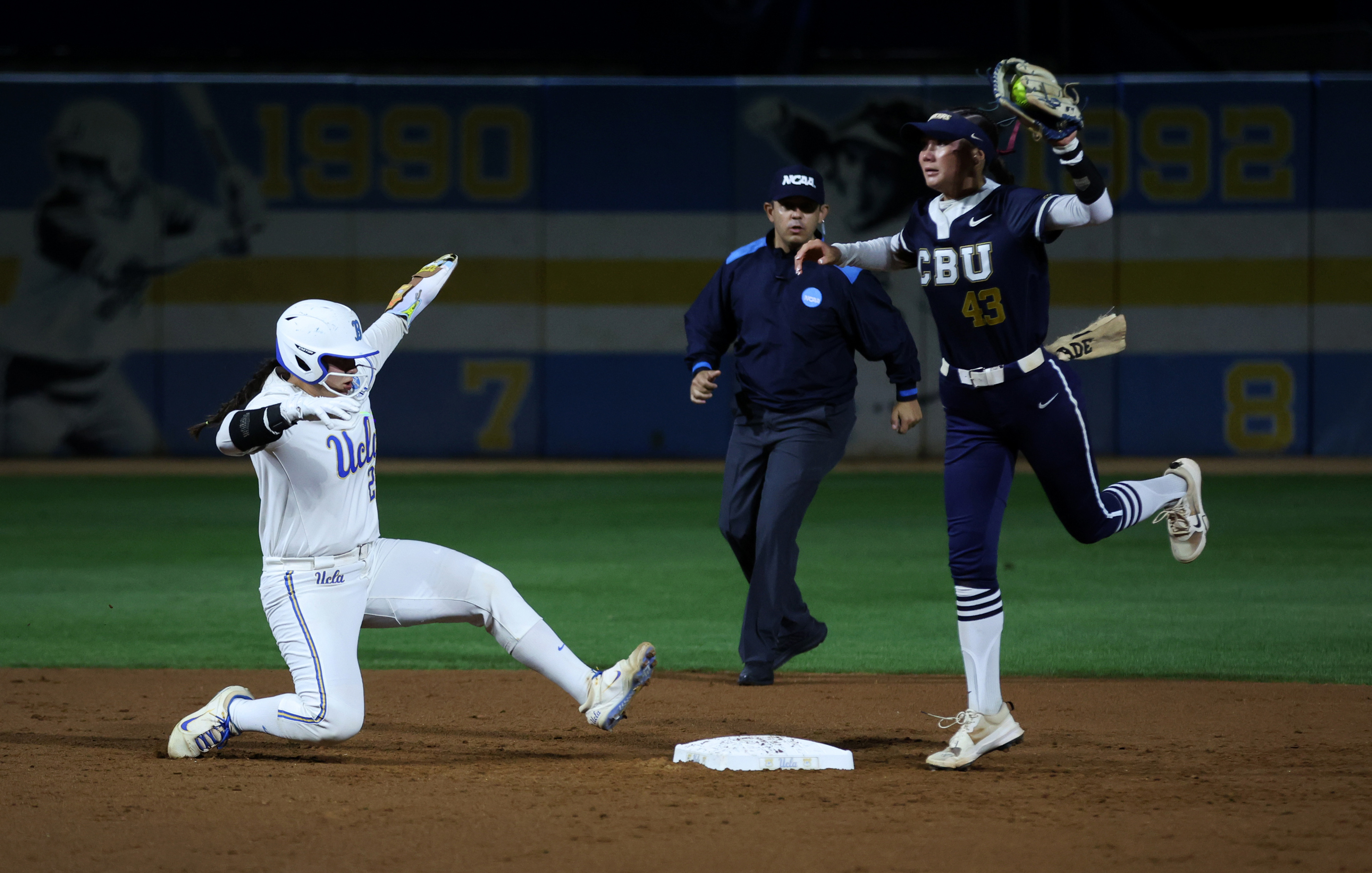UCLAâs Alexis Ramirez, left, leaps back toward second base to...