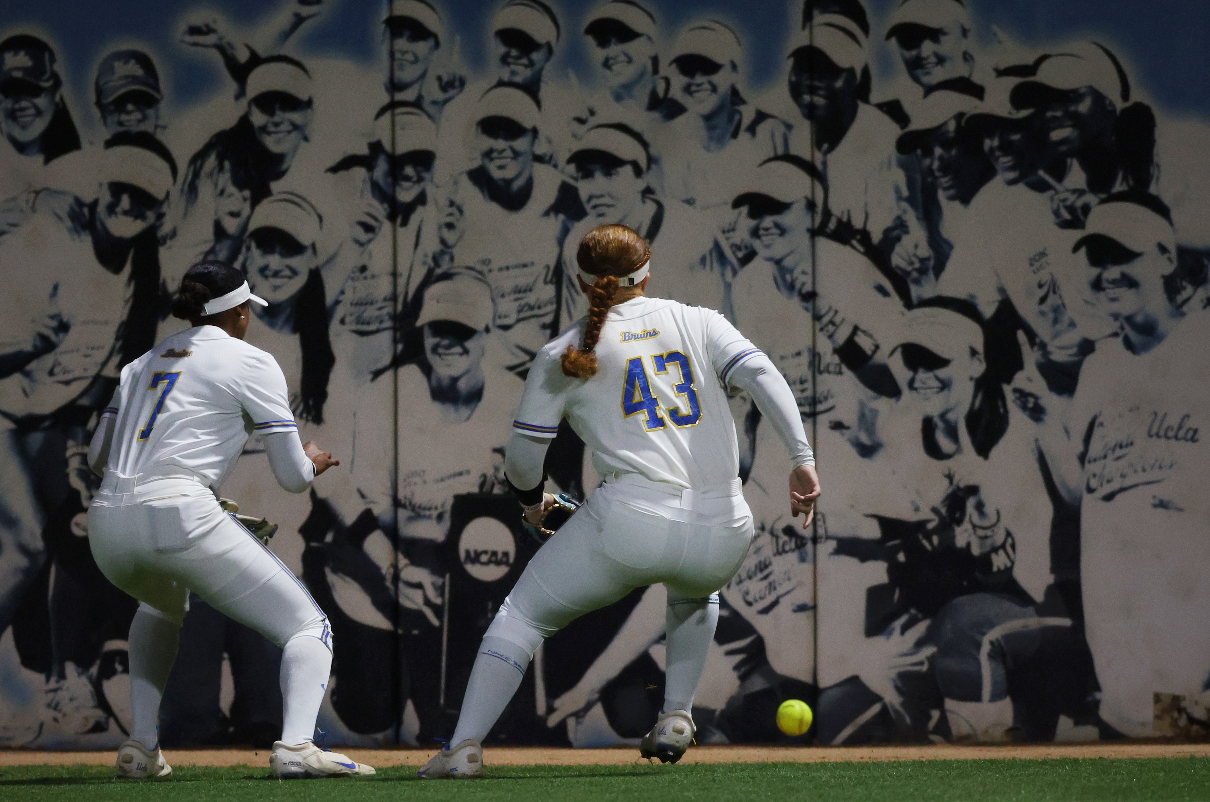 UCLA outfielders Jolyna Lamar, left, and Megan Grant scramble for...