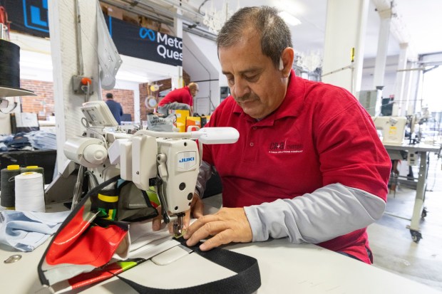 Carlos Garcia, an employee at CR&A Custom, sews a tote bag from discarded vinyl banners from LA Metro. (photo by Aurelia Ventura/LA Metro)