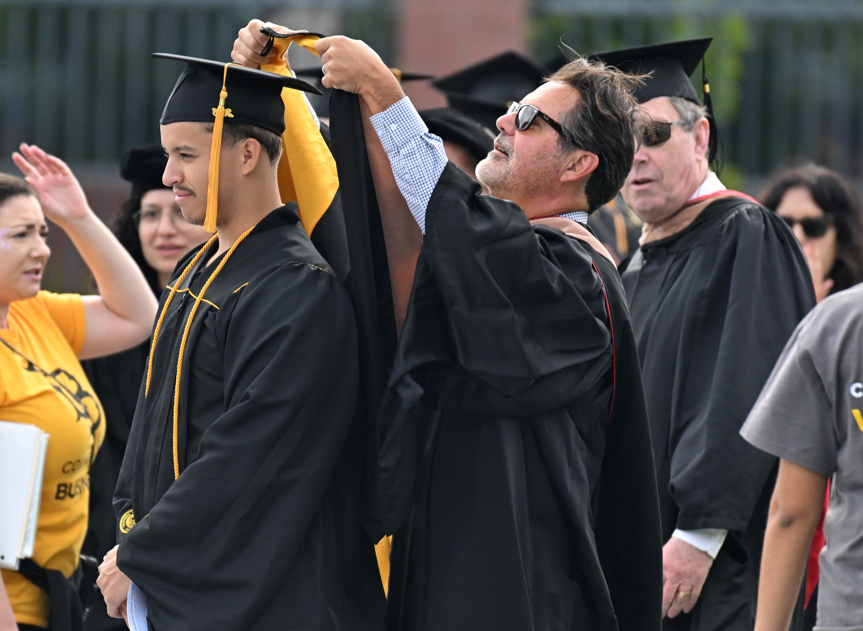 Professor Chris Marino places an academic hood over the head...