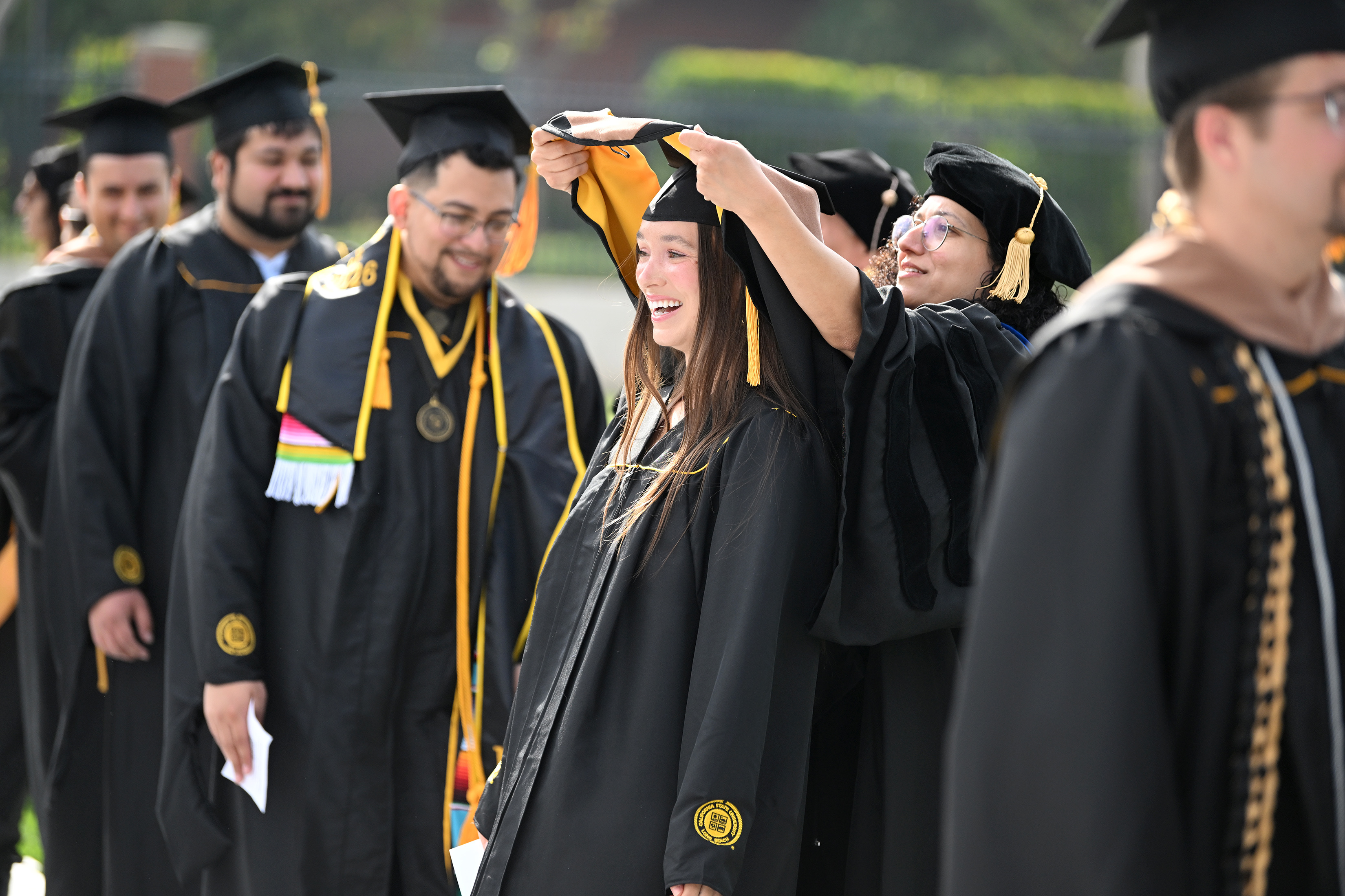 Dr. Mona Zanhour places an academic hood over the head...