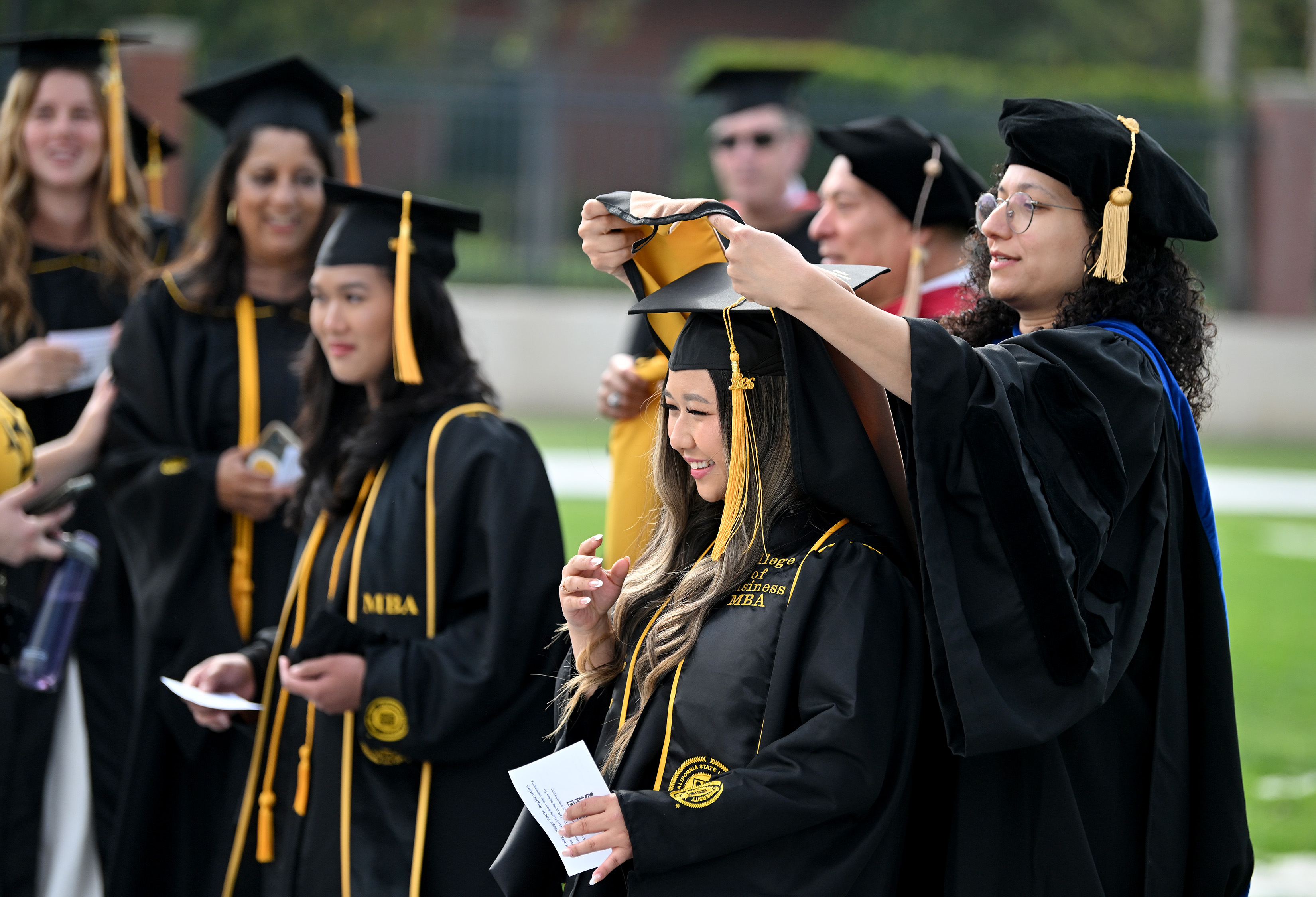 Dr. Mona Zanhour places an academic hood over the head...