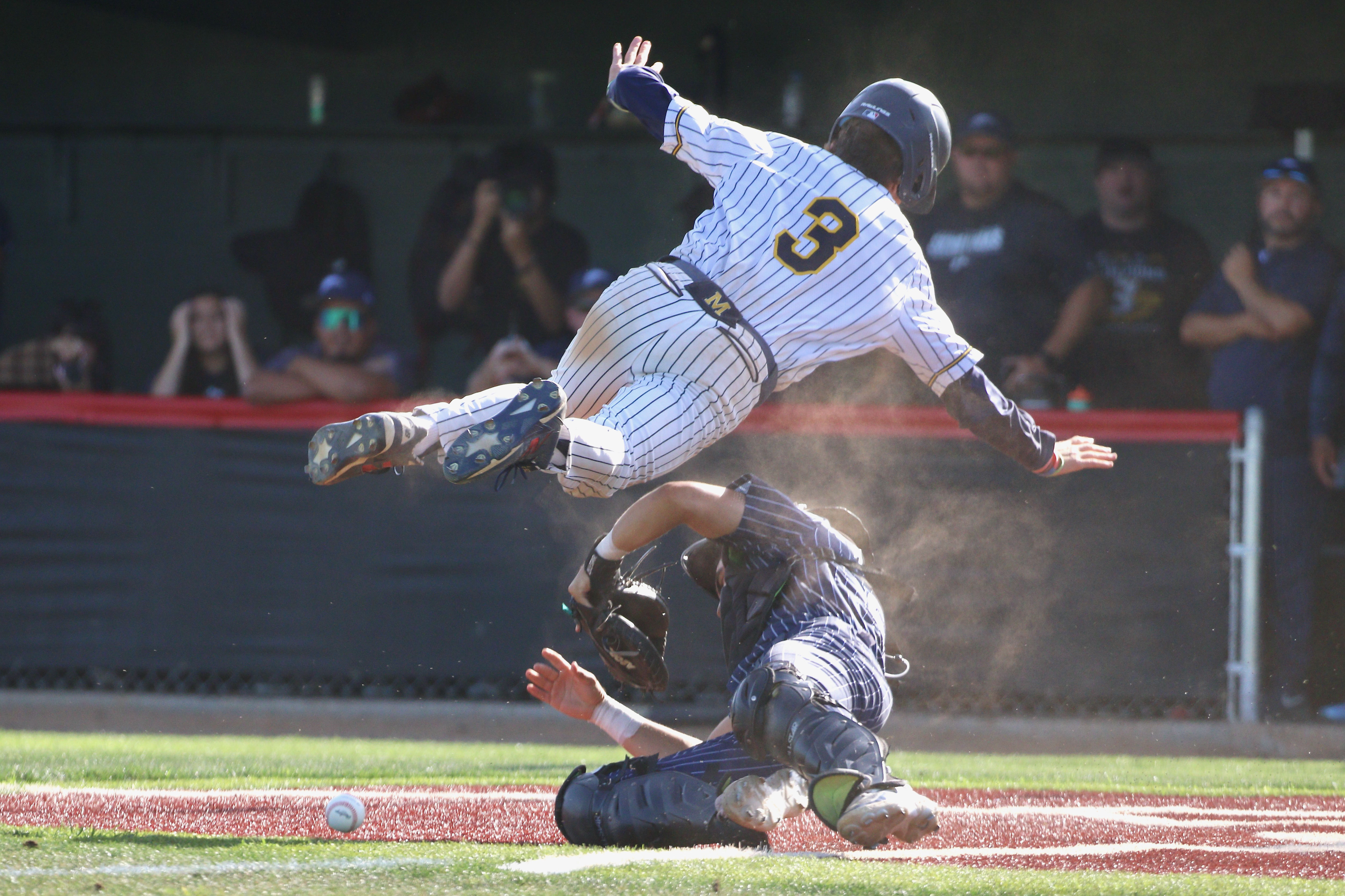 Millikan pinch-runner Maison Crommie leaps over Summit catcher Damian Lizarraga...